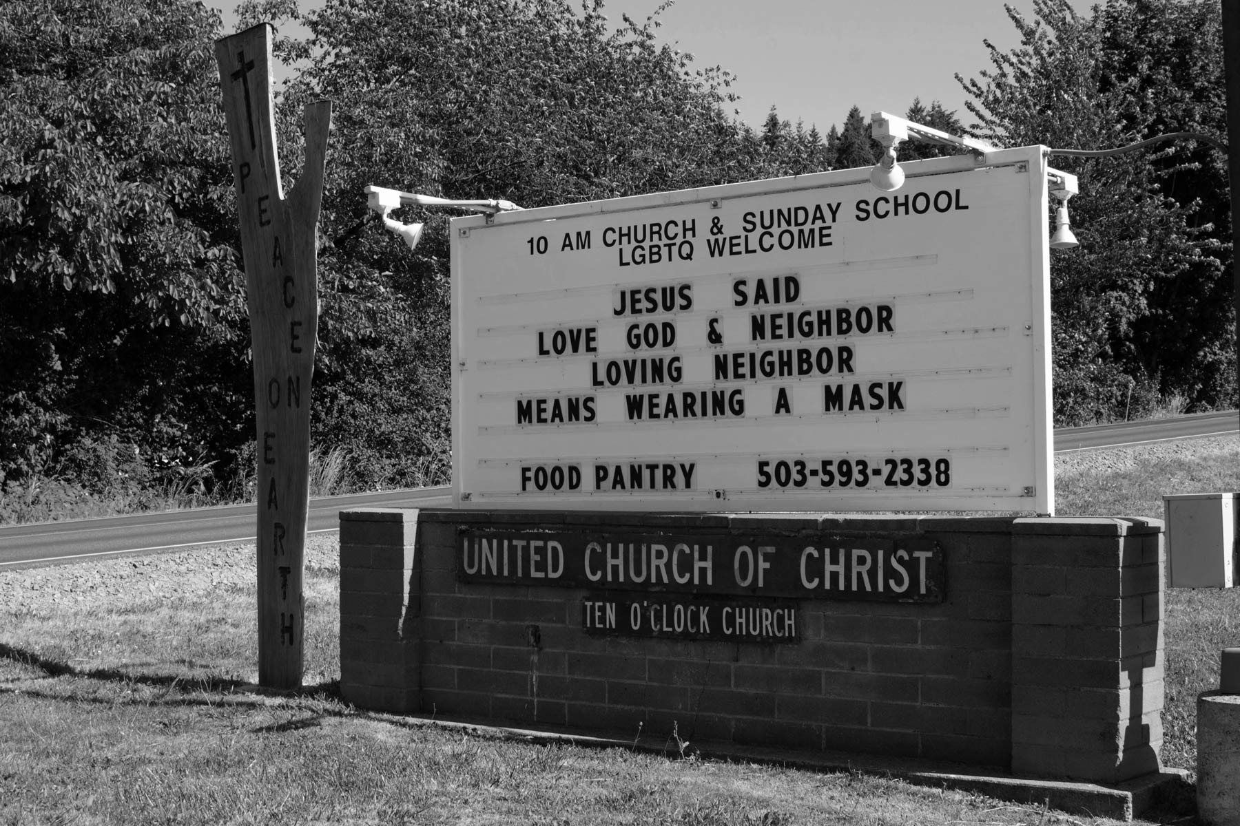 Readerboard outside the church reading Jesus said love God and neighbor, loving neighbor means wearing a mask, food pantry, wooden sign reads peace on earth